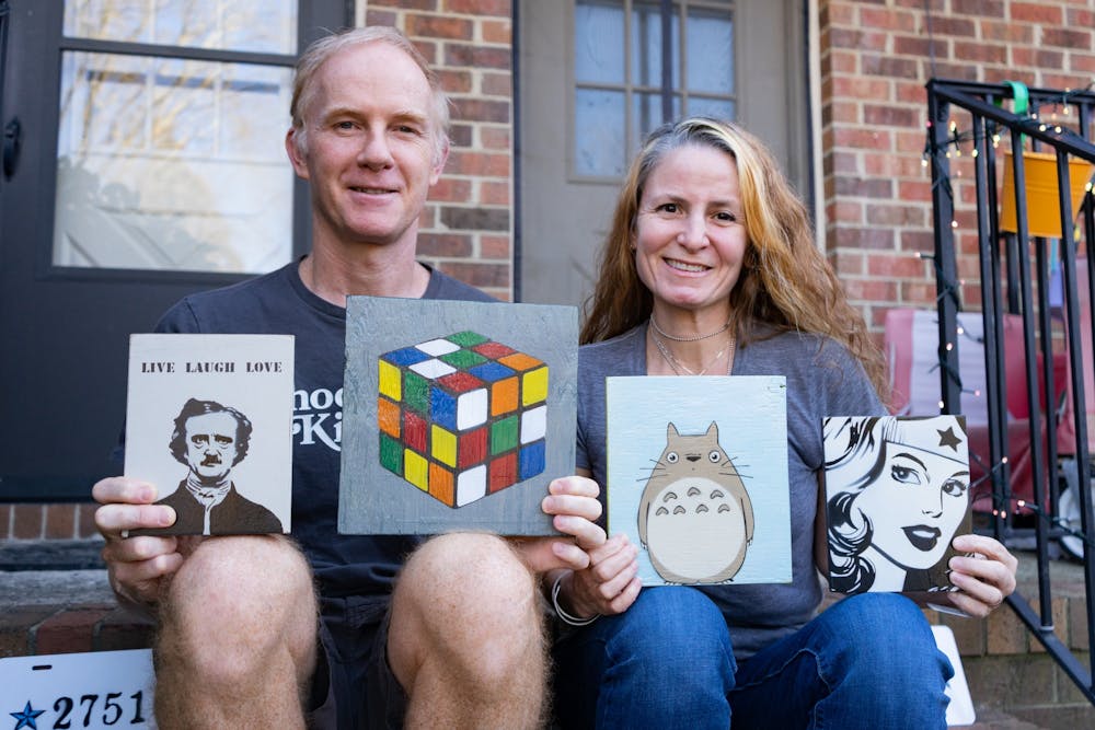 Duncan and Meg Morgan pose with their art on the front porch of their home in Carrboro on March 2, 2022. The two have been orchestrating The Bazaar Craft and Art Market for 7 years. The next market will be held on March 20 at Carrboro Commons.