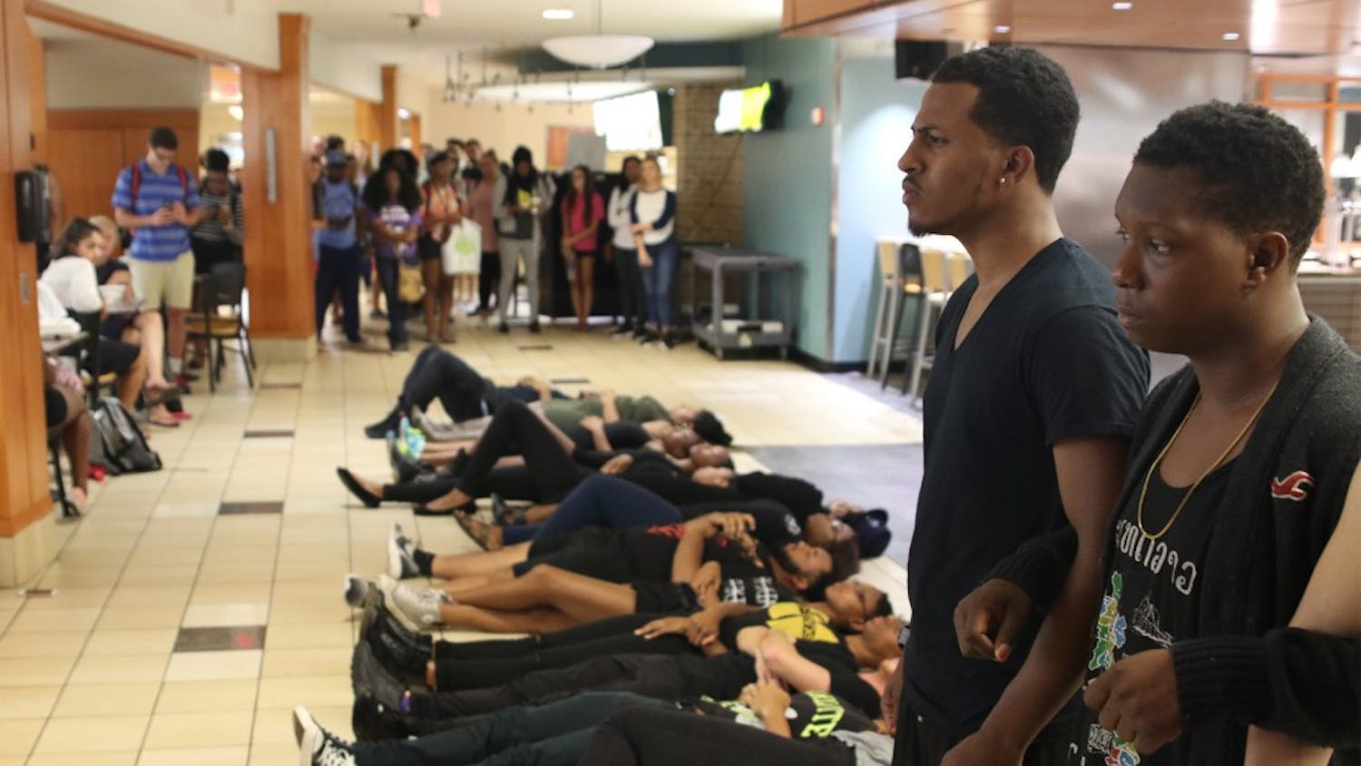Maurice Grier (near left) and&nbsp;Donavan Dicks stand with arms linked as they reach the end of their demonstration line in the bottom of Lenoir&nbsp;to protest police brutality.