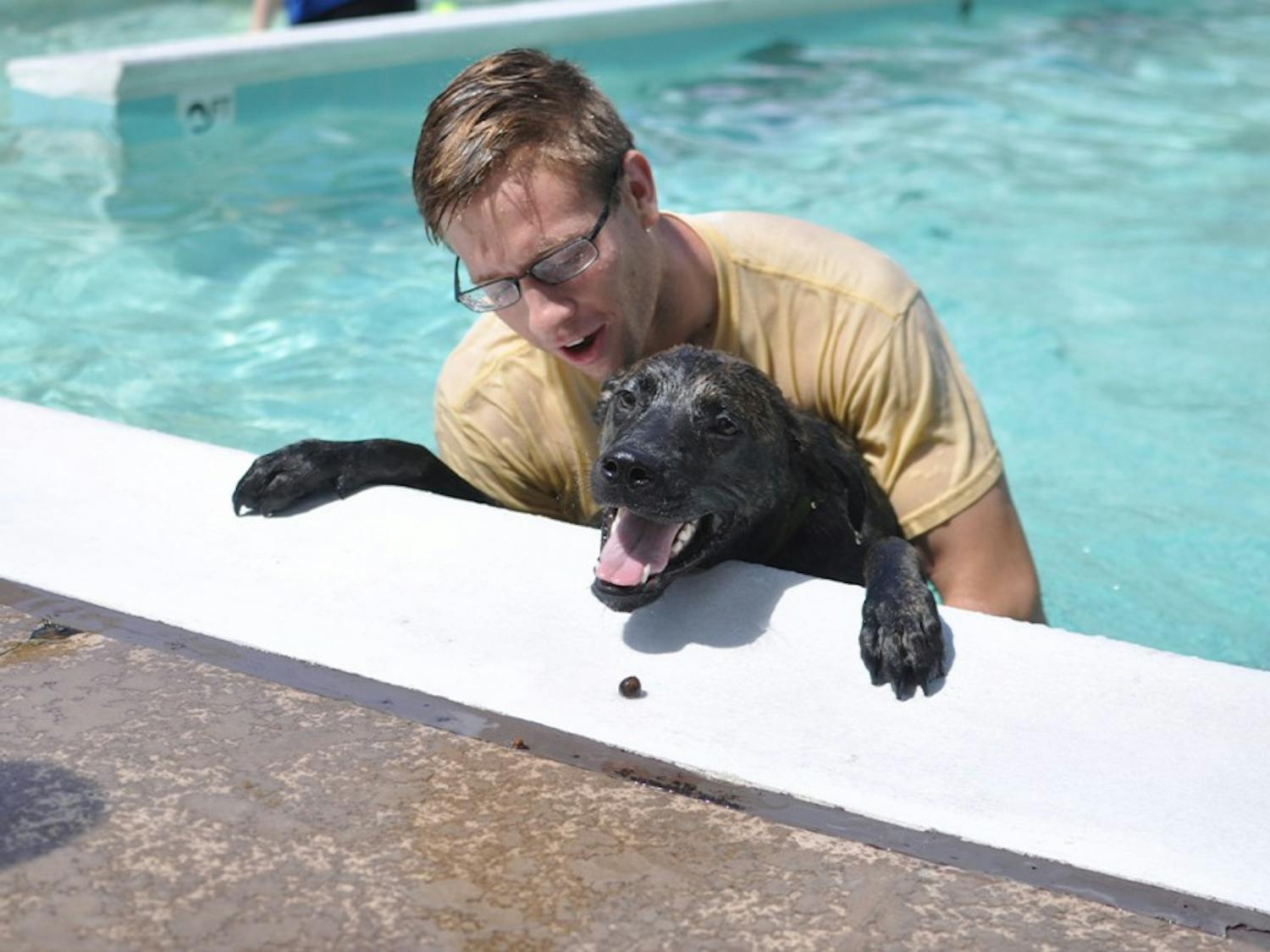 Jeff Lansford, a first year medical student at UNC, plays with 9-month-old Boxer mix Moose Sunday afternoon at Hargraves Community Center's A.D. Clark Pool.