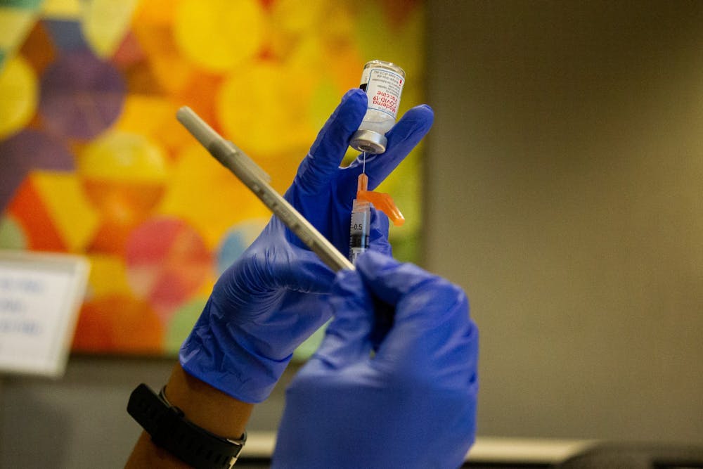 <p>Christian Brown, a second year pharmacy student, taps a syringe with a pen to rid it of any air bubbles while preparing a dose of the Moderna COVID-19 vaccine on Thursday, Jan. 21, 2021 in the Friday Center in Chapel Hill.</p>