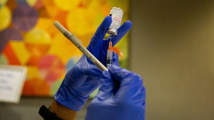 Christian Brown, a second year pharmacy student, taps a syringe with a pen to rid it of any air bubbles while preparing a dose of the Moderna COVID-19 vaccine on Thursday, Jan. 21, 2021 in the Friday Center in Chapel Hill.