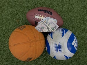 DTH Photo Illustration. A bill proposed in the North Carolina House of Representatives would legalize sports betting for college and professional sports in the state. Money is picturing on top of sports balls outside of Dorrance Field on Monday, March 27, 2023.