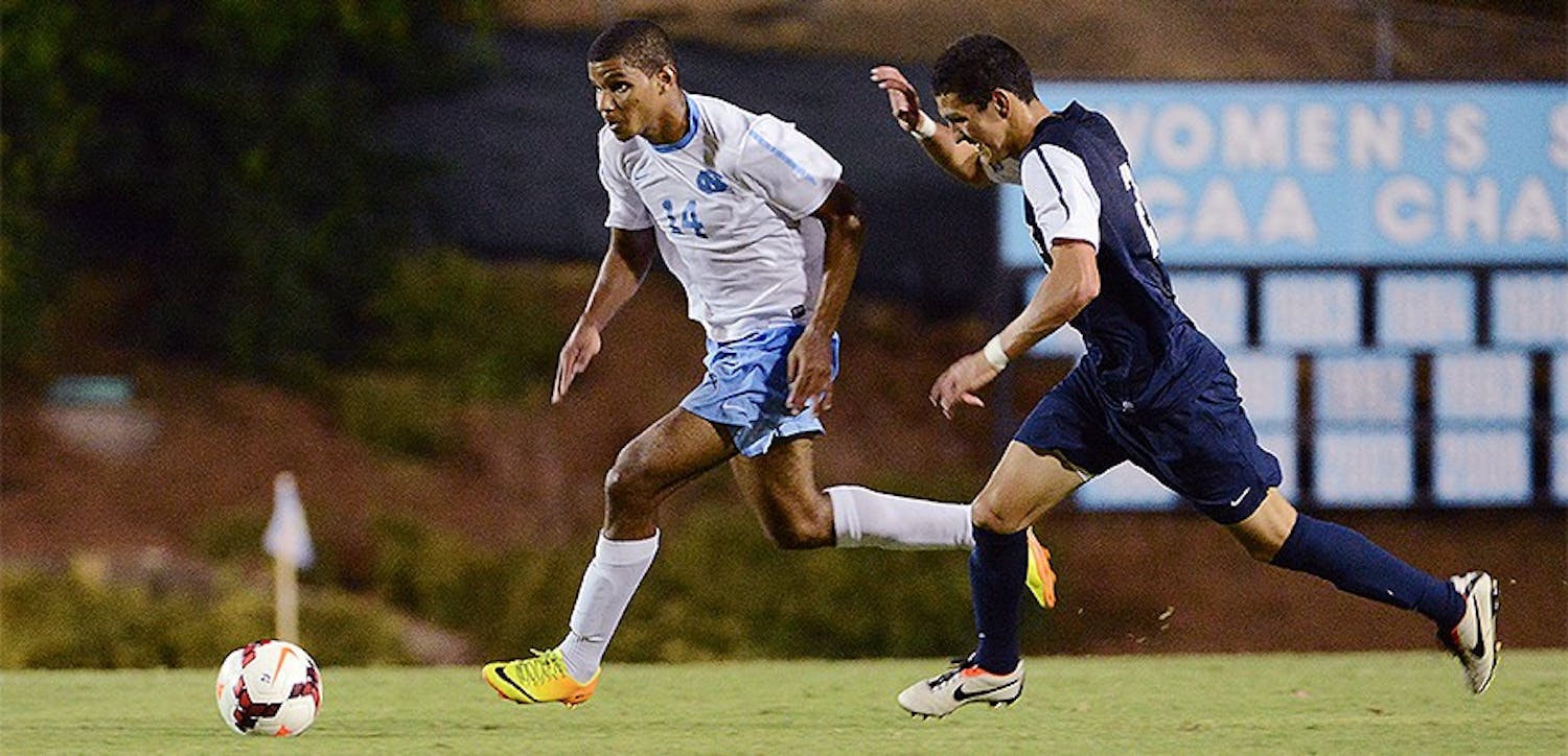 UNC midfielder Omar Holness (14) dribbles the ball up field as a Monmouth defender applies pressure.