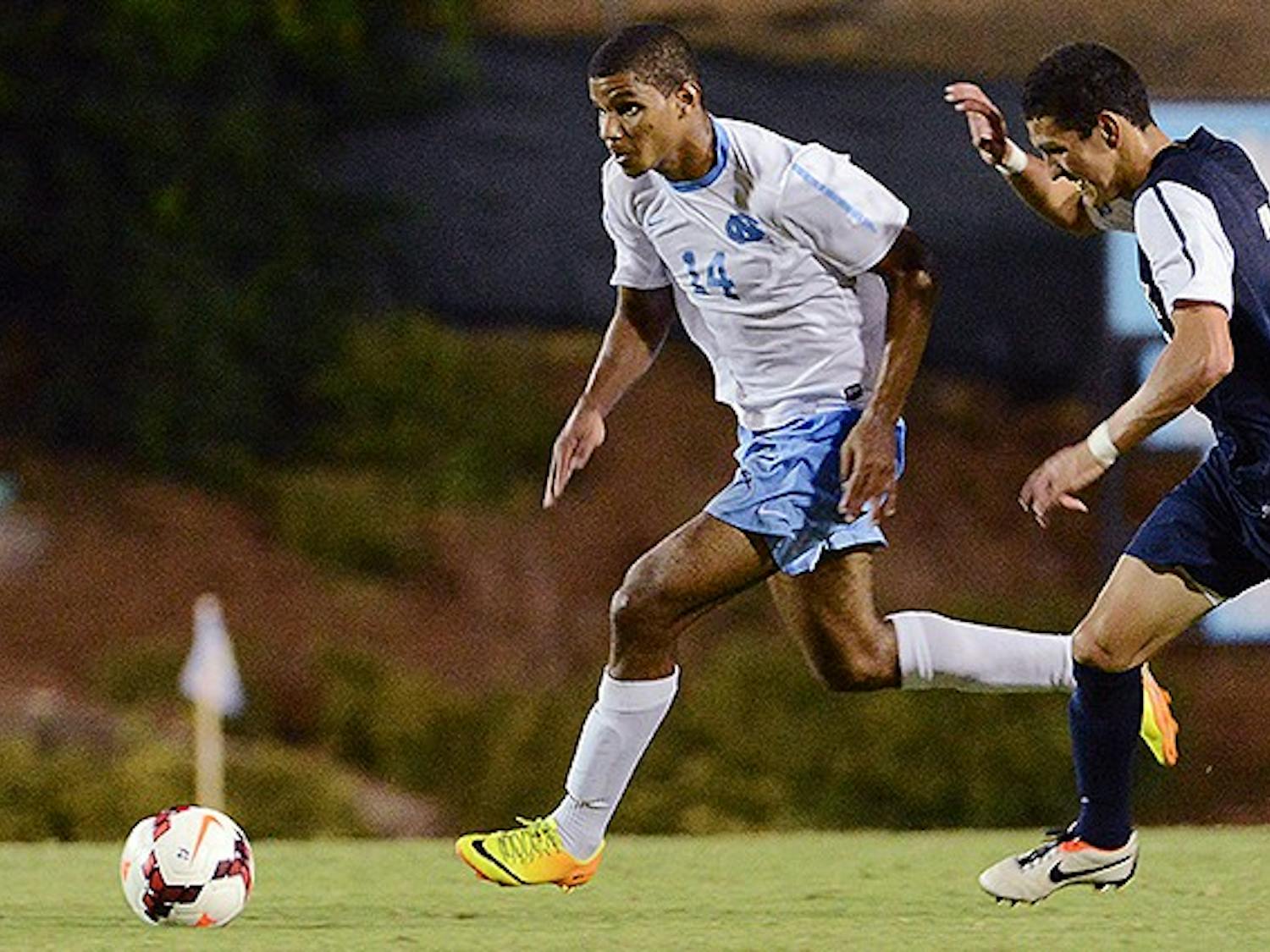 UNC midfielder Omar Holness (14) dribbles the ball up field as a Monmouth defender applies pressure.