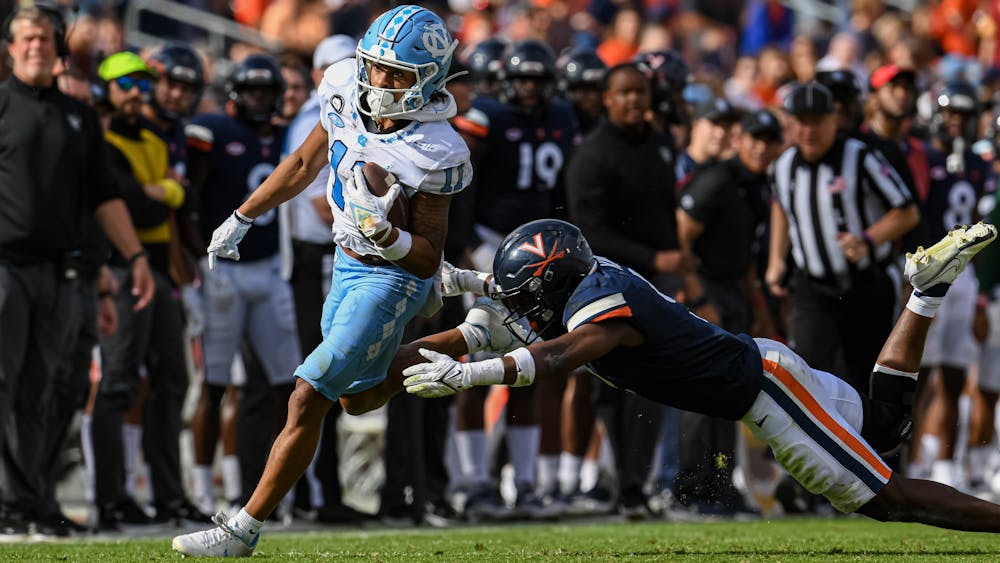 UNC junior wide receiver Josh Downs (11) runs from the grasp of an opposing player during the football game against Virginia at Scott Stadium in Charlottesville, V.A. on Saturday, Nov. 5, 2022. UNC beat Virginia 31-28. 
Photo Courtesy of Jeremy Sharpe.