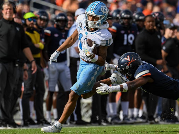 UNC junior wide receiver Josh Downs (11) runs from the grasp of an opposing player during the football game against Virginia at Scott Stadium in Charlottesville, V.A. on Saturday, Nov. 5, 2022. UNC beat Virginia 31-28. 
Photo Courtesy of Jeremy Sharpe.