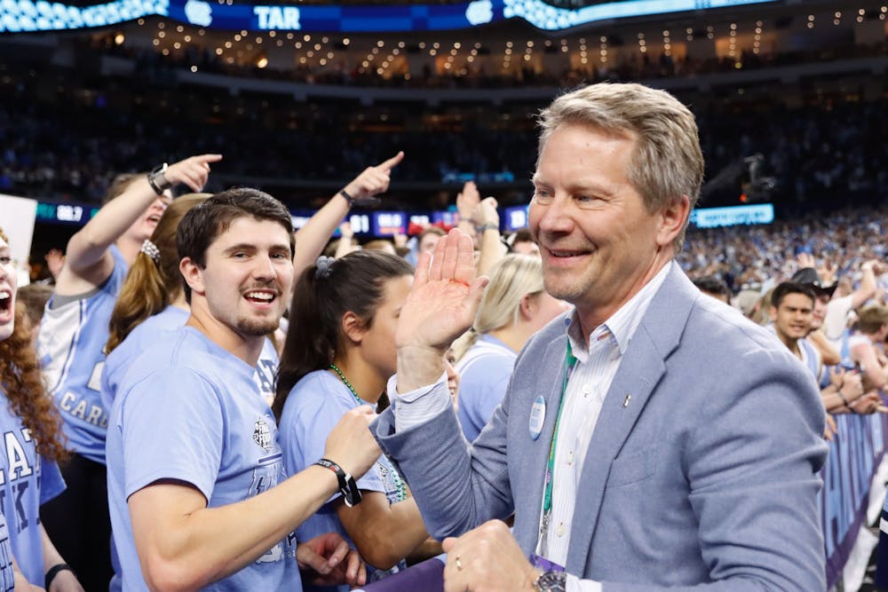 Kevin Guskiewicz, chancellor of UNC-Chapel Hill, celebrates with students after a Carolina victory in the Final Four of the NCAA Tournament against Duke in New Orleans on Saturday, April 2, 2022. UNC won 81-77.