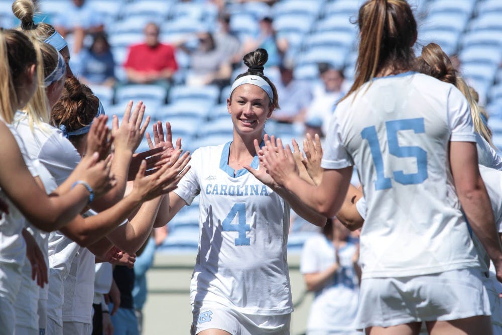 <p>Marie McCool high fives her teammates before the team's Senior Day game against Duke on April 21, 2018 at Kenan Stadium.</p>