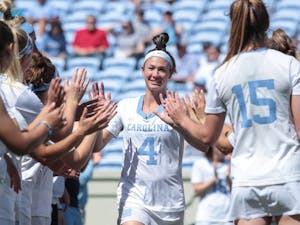 Marie McCool high fives her teammates before the team's Senior Day game against Duke on April 21, 2018 at Kenan Stadium.