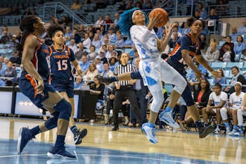 UNC redshirt senior guard Madinah Muhammed (3) aims for the hoop with University of Virginia first-year guard Shemera Williams (10) on defense. The Tar Heels beat the Cavaliers 78-68 in Carmichael Arena on Jan. 30, 2020.