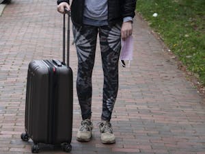 DTH Photo Illustration. A UNC student holds a suitcase and a surgical mask on campus on Tuesday, March 3, 2020. Students are unsure how the coronavirus will affect their plans to study abroad.