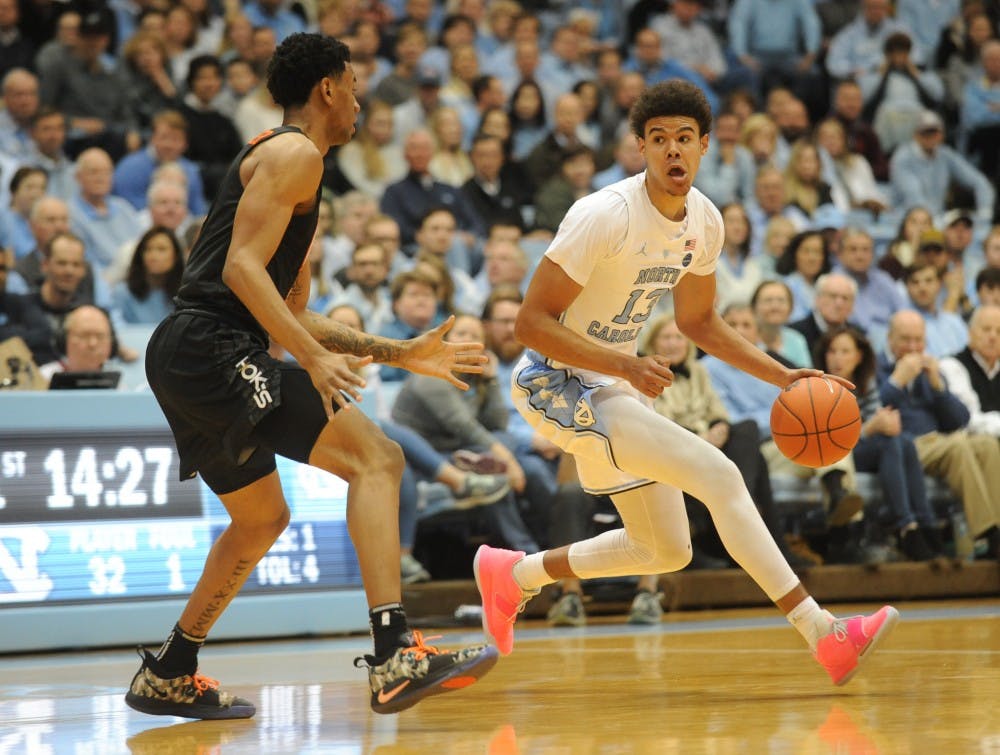 <p>UNC graduate guard Cameron Johnson (13) evades Virginia Tech sophomore guard Nickeil Alexander-Walker (4) to make a pass at the Smith Center on Monday, Jan. 21, 2019. The Tar Heels won the game 103-82.</p>