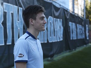 UNC men's tennis player Robert Kelly poses for a photo while wearing a "Mick" badge on his arm to commemorate Mick Macholl, a 5-year-old super fan of the team&nbsp;who died on Dec. 13&nbsp;after an 18-month battle with neuroblastoma.