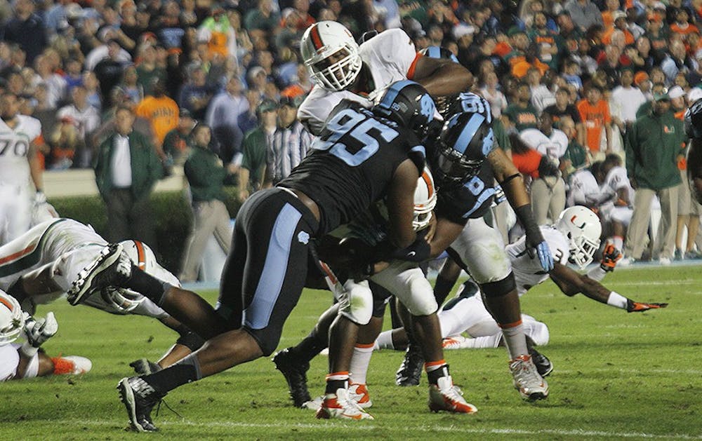 	Kareem Martin (95), a senior defensive end, assists a teammate in tackling a player during the game against Miami on Oct. 17. Martin won the ACC’s defensive lineman of the week for his performance.