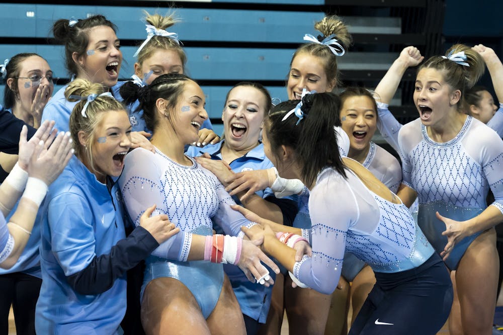 UNC Sophomore Lali Dekanoidze celebrates with her team after scorring a 9.975 on the uneven bars setting a program record during the meet against NC State at Carmichael Arena on Monday Jan. 9, 2023. UNC beat NC State 196.2 to 195.5.
