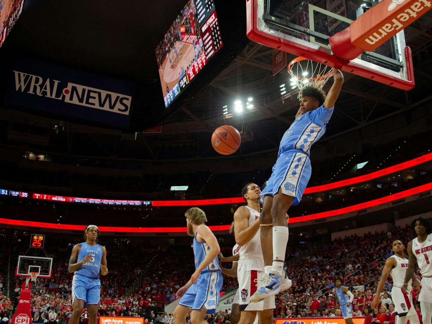 Sophomore guard Puff Johnson (14) hangs on the basketball hoop after a goal during UNC's rivalry game against NC State on Feb. 26, 2022. UNC won that game 84-74.
