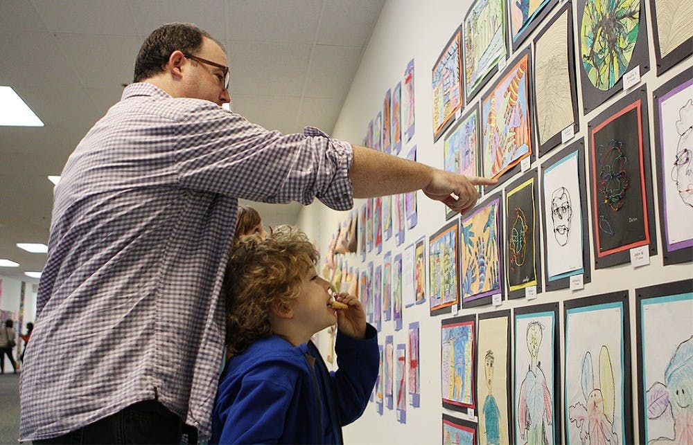 Patrick Herron and his son, Booker, 7, look at the student created artwork on display at University Mall on Saturday. Booker is a student at Estes Hill Elementary School. 