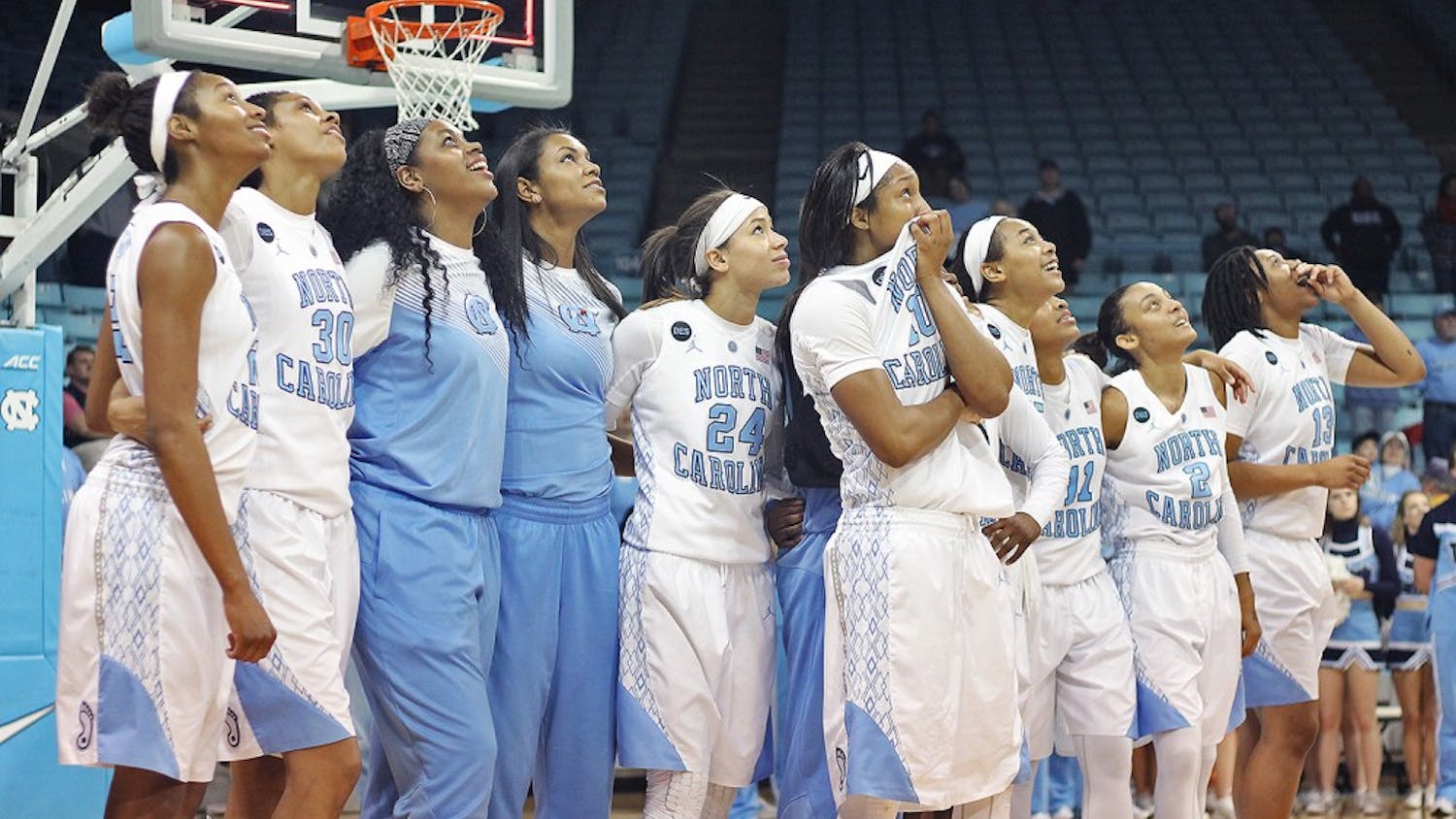 The women's basketball team links arms as the Tar Heels watch a highlight reel on their senior night Feb. 26.