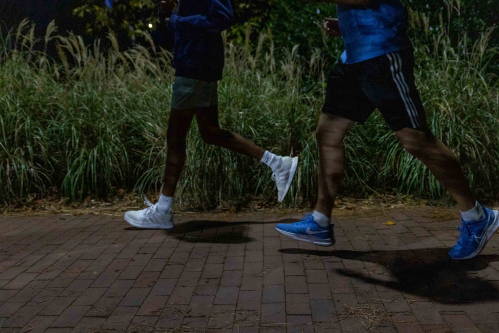 DTH Photo Illustration. Two UNC students take a nighttime jog, photographed on Wednesday, Oct. 26, 2022. The Franklin All Nighter, an all-night charity run, will take place in the first week of November.