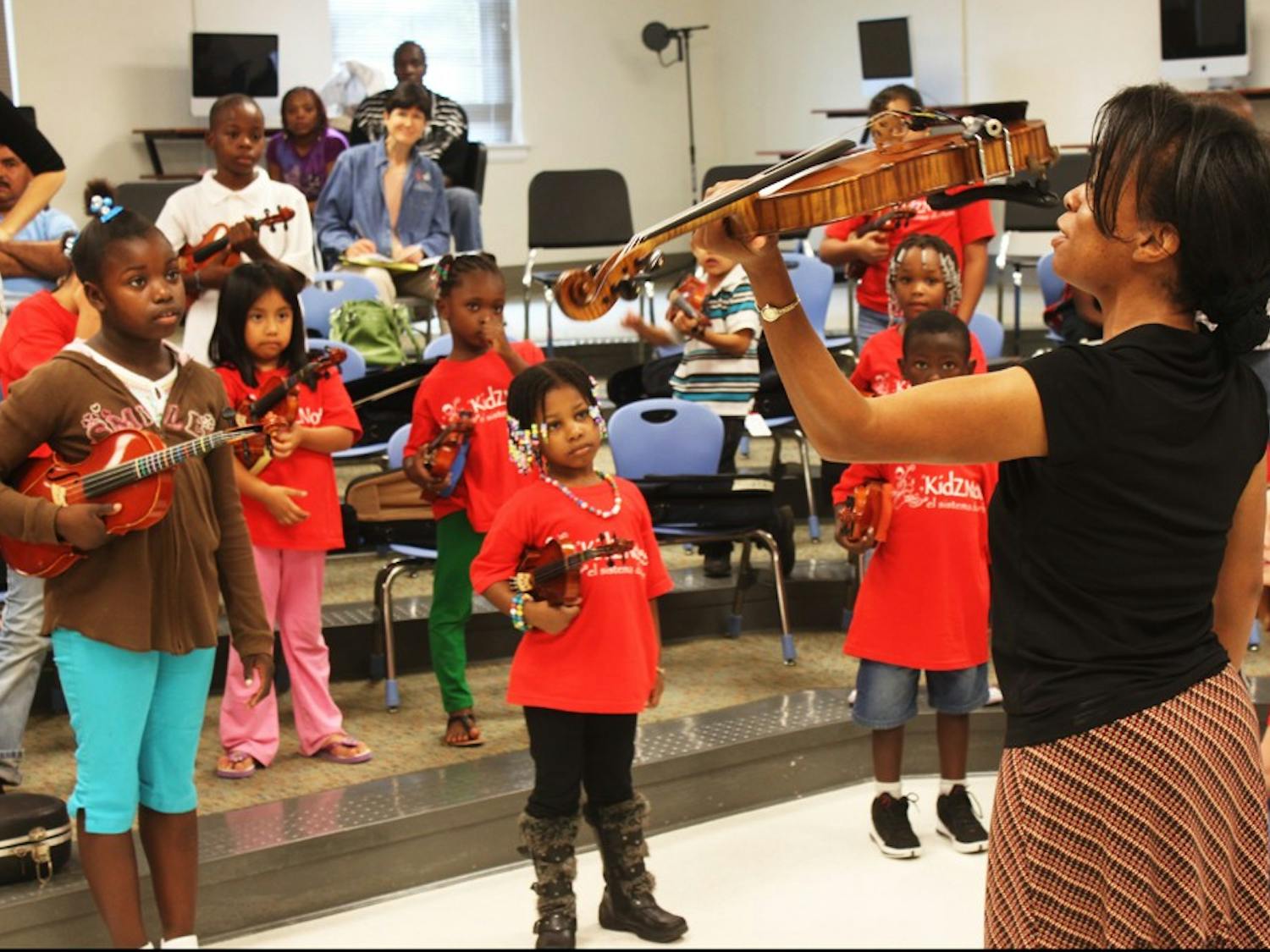Tonya Suggs, the string orchestra educator at Wake County Public Schools, demonstrates the proper technique for holding a violin as part of the KidZNotes program to give needy children musical training.
