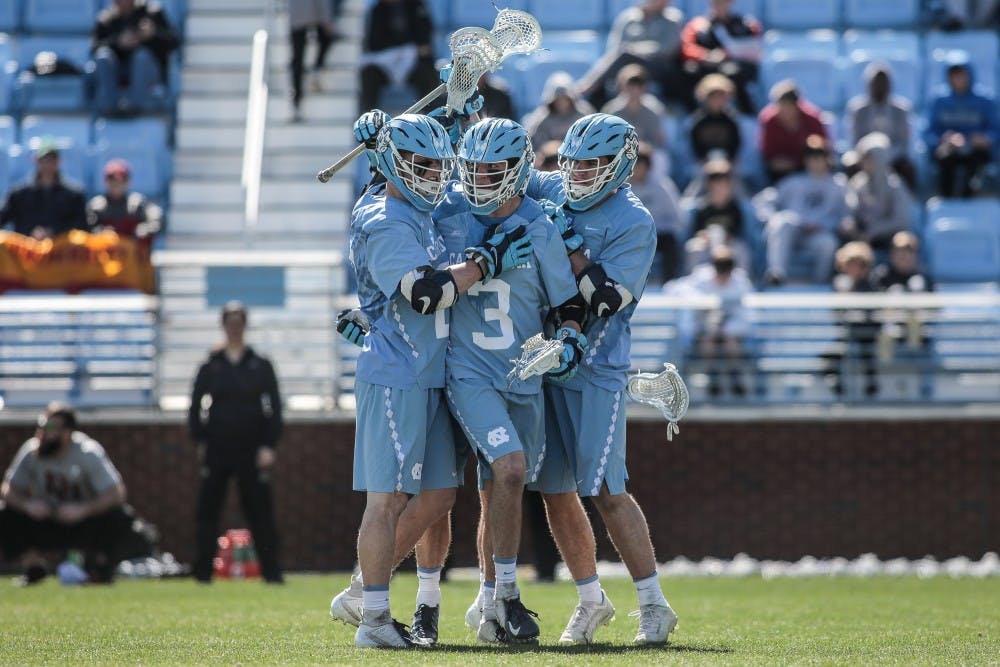 <p>UNC junior midfielder William Perry (3) celebrates after scoring a goal with teammates Justin Anderson (21) and Andy Matthews (12) during UNC's 12-10 home loss against the University of Denver on Saturday, March 3, 2019 at the UNC Soccer and Lacrosse Stadium in Chapel Hill, N.C. This was the UNC Men's Lacrosse team's inaugural game at the UNC Soccer and Lacrosse Stadium.</p>