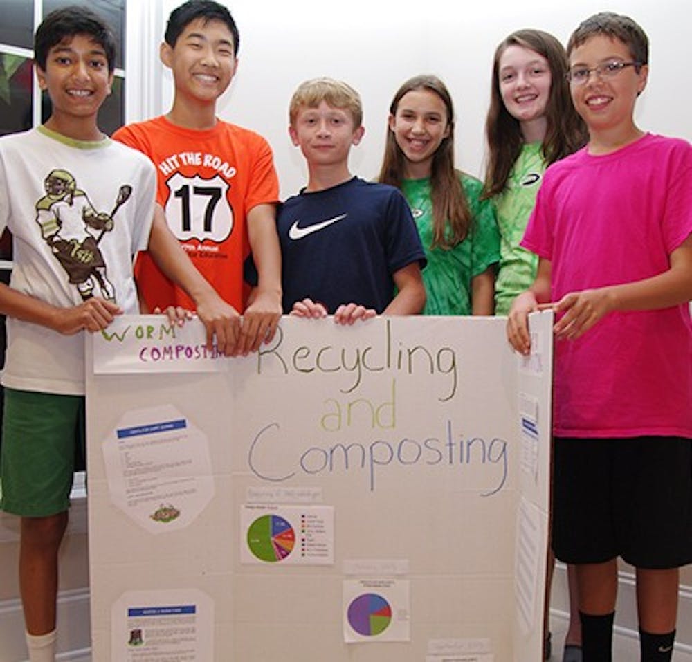 Middle School students stand in front of a compost bin and a poster displaying information on their compost and recycling project. 

Student names--ask Chloe. 