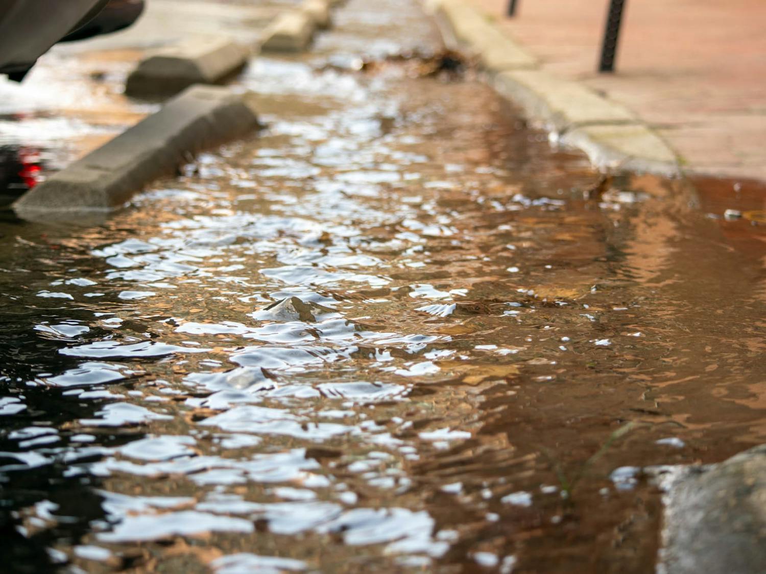 Water flows onto the sidewalk near UNC's Carrington Hall on Thursday, Feb. 23, 2023.
