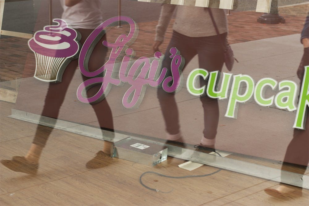 UNC students walk by  the window display of Gigi’s Cupcakes on West Franklin Street,. Gigi’s closed permanently on Saturday due to low sales.