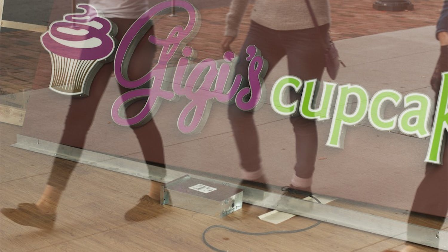 UNC students walk by  the window display of Gigi’s Cupcakes on West Franklin Street,. Gigi’s closed permanently on Saturday due to low sales.