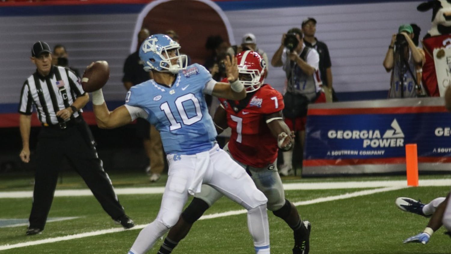 UNC quarterback Mitch Trubisky (10) prepares to unload a deep pass while being pressured by Georgia outside line backer Lorenzo Carter (7).&nbsp;The Tar Heels fell to the Bulldogs 33-24 on Saturday in Atlanta.