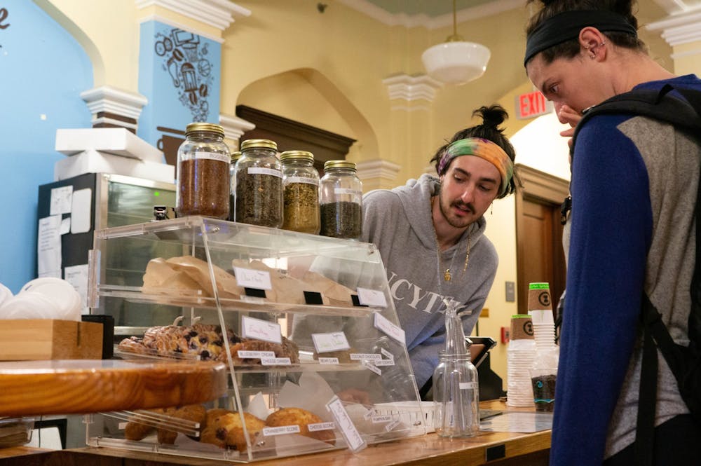 John Vance, a junior at UNC and barista at the student-run Meantime Coffee Company, helps a customer select a pastry in the Campus Y on Thursday, Jan 16, 2020. 100% of profits from Meantime are going to help the wildfire crisis in Australia.