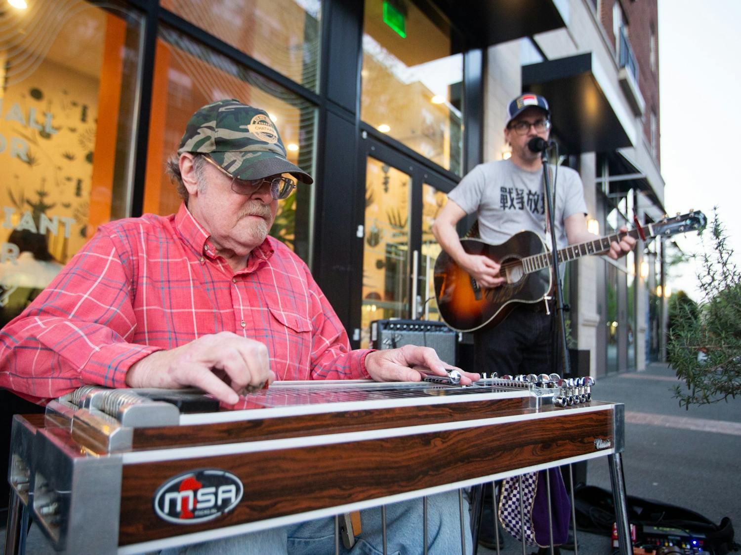 Musicians Clark Albert Blomquist and Steven Watson perform outside Roots Natural Kitchen on Franklin Street in Chapel Hill, N.C. on Saturday, April 1, 2023. The performance was part of the Downtown Live series, which features local musicians in outdoor settings in downtown Chapel Hill.