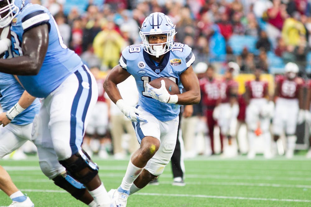 <p>Graduate transfer running back Ty Chandler (19) carries the ball at the Duke's Mayo Bowl against South Carolina at the Bank of America Stadium in Charlotte on Dec. 30, 2021. UNC lost 38-21.</p>