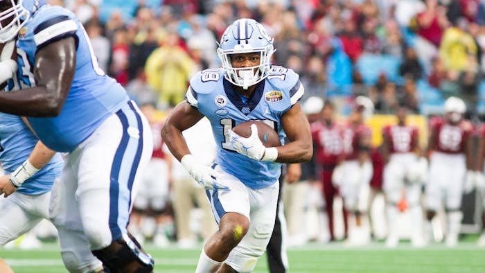 Graduate transfer running back Ty Chandler (19) carries the ball at the Duke's Mayo Bowl against South Carolina at the Bank of America Stadium in Charlotte on Dec. 30, 2021. UNC lost 38-21.