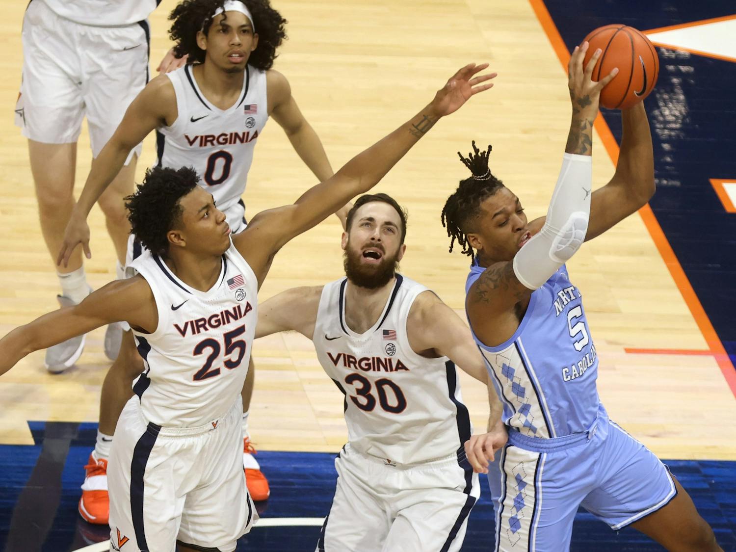 North Carolina forward Armando Bacot (5) grabs the rebound next to Virginia forward Jay Huff (30) and Virginia guard Trey Murphy III (25) during the game Saturday in Charlottesville. Photo courtesy of Andrew Shurtleff/The Daily Progress.