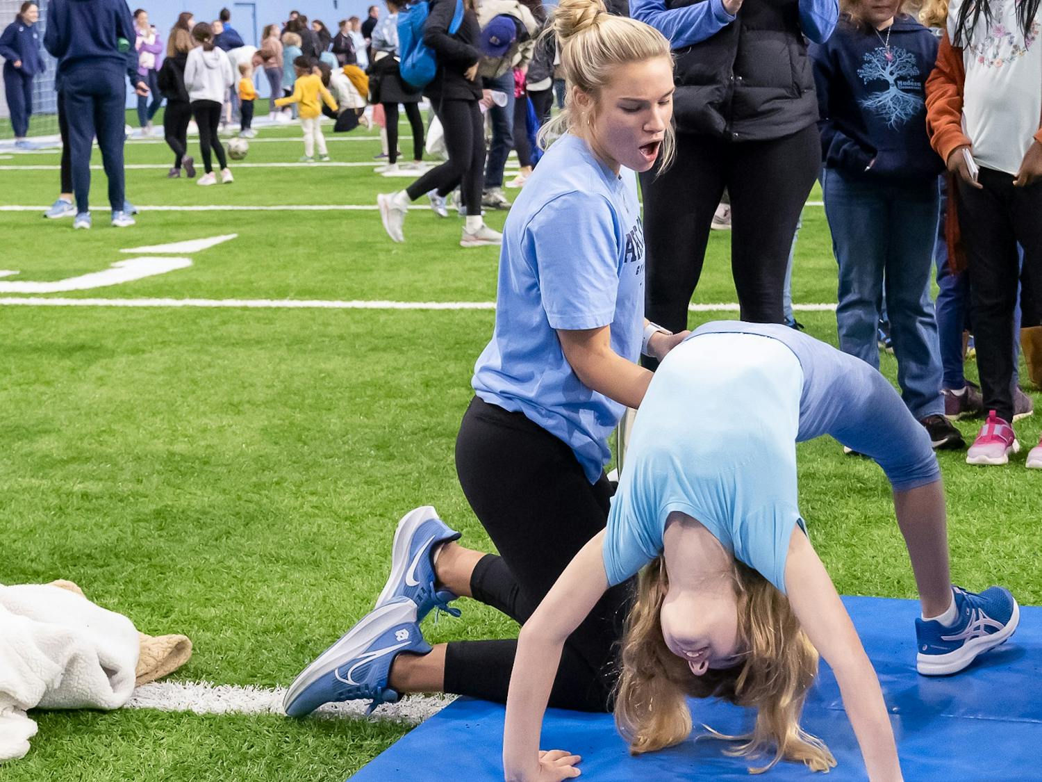 UNC senior gymnast Hallie Thompson helps Bailee Peterson do a backflip at the National Girls & Women in Sports Day event held at the Bill Koman Practice on Sunday, Jan. 22, 2023.