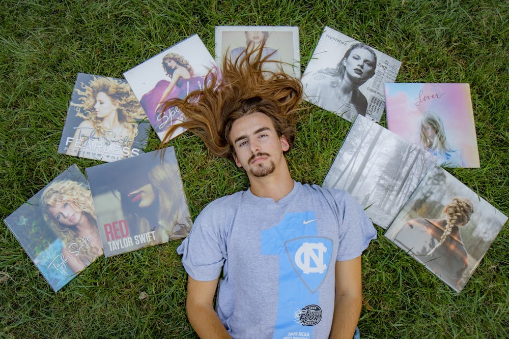 <p>DTH Photo Illustration. Assistant Photo Editor and Resident Taylor Swift Expert Ira Wilder lays in the grass with his collection of Taylor Swift vinyls.</p>