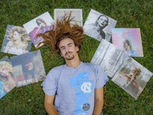 DTH Photo Illustration. Assistant Photo Editor and Resident Taylor Swift Expert Ira Wilder lays in the grass with his collection of Taylor Swift vinyls.