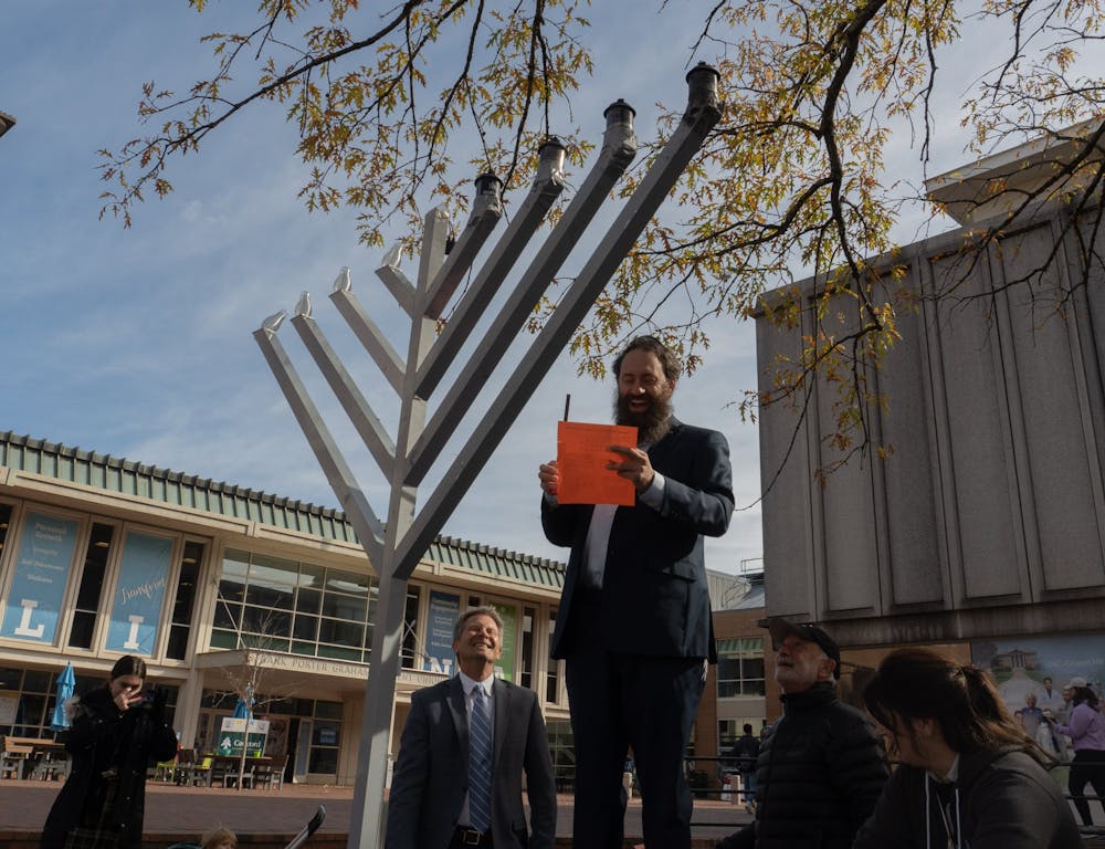 Rabbi Zalman Bluming of UNC Chabad reads a prayer in preparation for the candle lighting in the pit on Monday, Nov. 29, 2021, as Chancellor Kevin Guskiewicz watches from below.