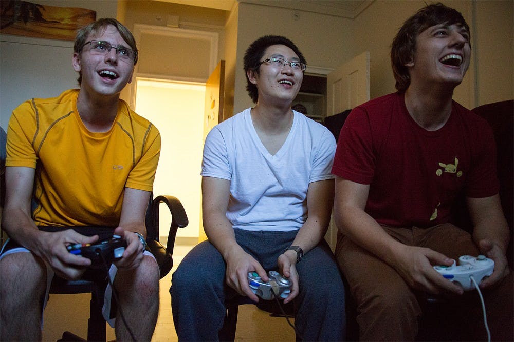 Freshman Jimmy Messmer, left, graduate student Weilin Zou, and senior Tyler Crews play the video game Super Smash Bros. in an Everett dorm room. Inspired by the 2013 film "Super Smash Bros.," members compete against one another in each others dorm rooms, referred to as "smash houses" by the group, and in common areas where a television is present.