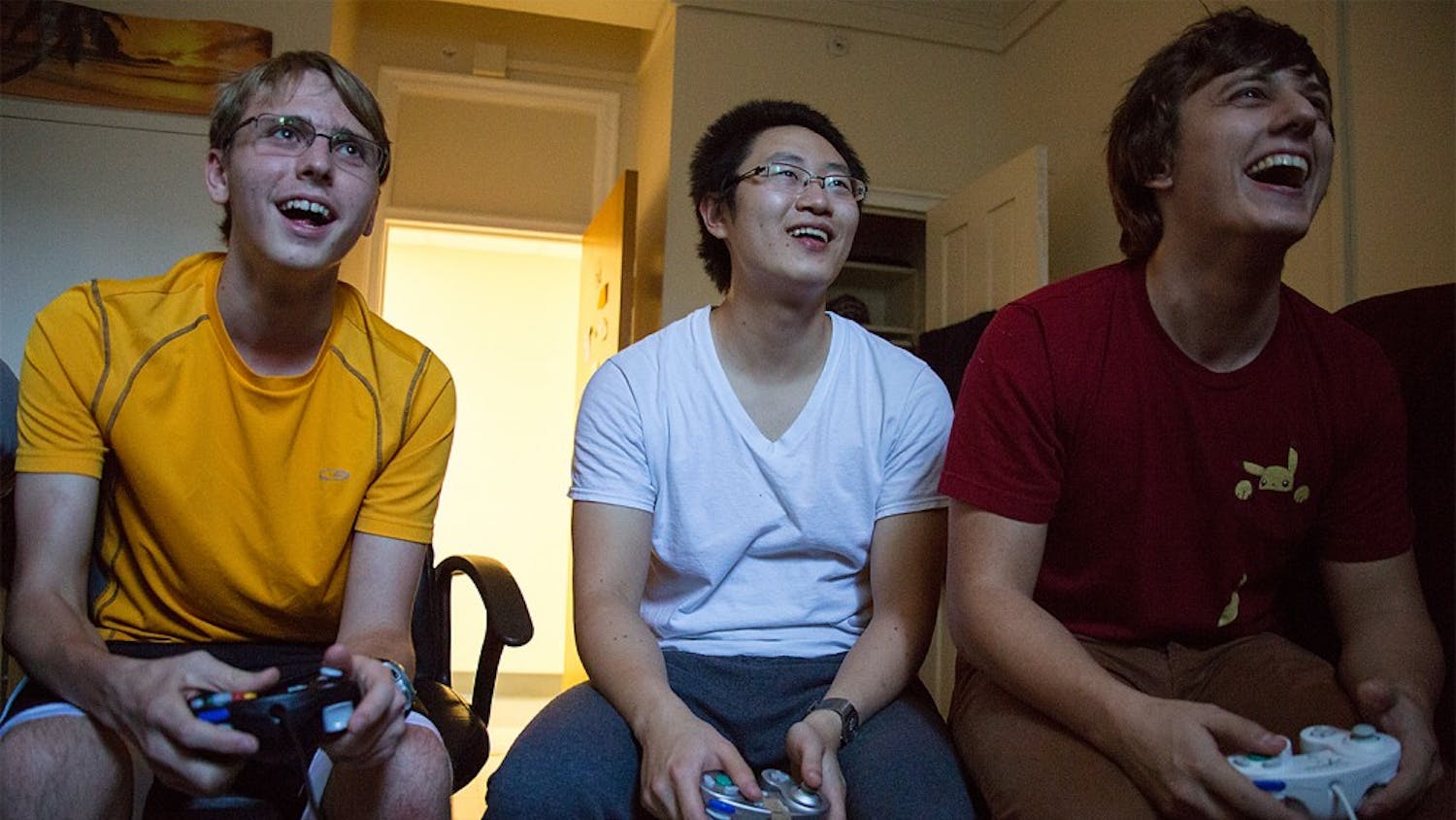Freshman Jimmy Messmer, left, graduate student Weilin Zou, and senior Tyler Crews play the video game Super Smash Bros. in an Everett dorm room. Inspired by the 2013 film "Super Smash Bros.," members compete against one another in each others dorm rooms, referred to as "smash houses" by the group, and in common areas where a television is present.