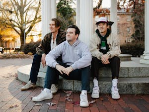 Dylan Melisaratos (middle), a senior Business Administration major, poses for a portrait with his friends James Toole and Matthew Sullivan at the Old Well on Monday, Nov. 29, 2021.