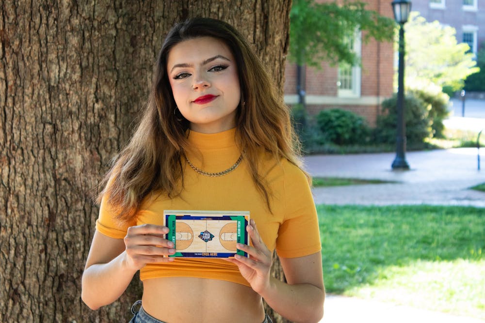 Junior Environmental Justice major and member of the UNC Marching Tar Heels, Gabriela Duncan holds up her personal piece of the Roy Williams Court on Sunday, April 24, 2022. Duncan has played alto saxophone for twelve years and has been in The Marching Tar Heels since coming to UNC.