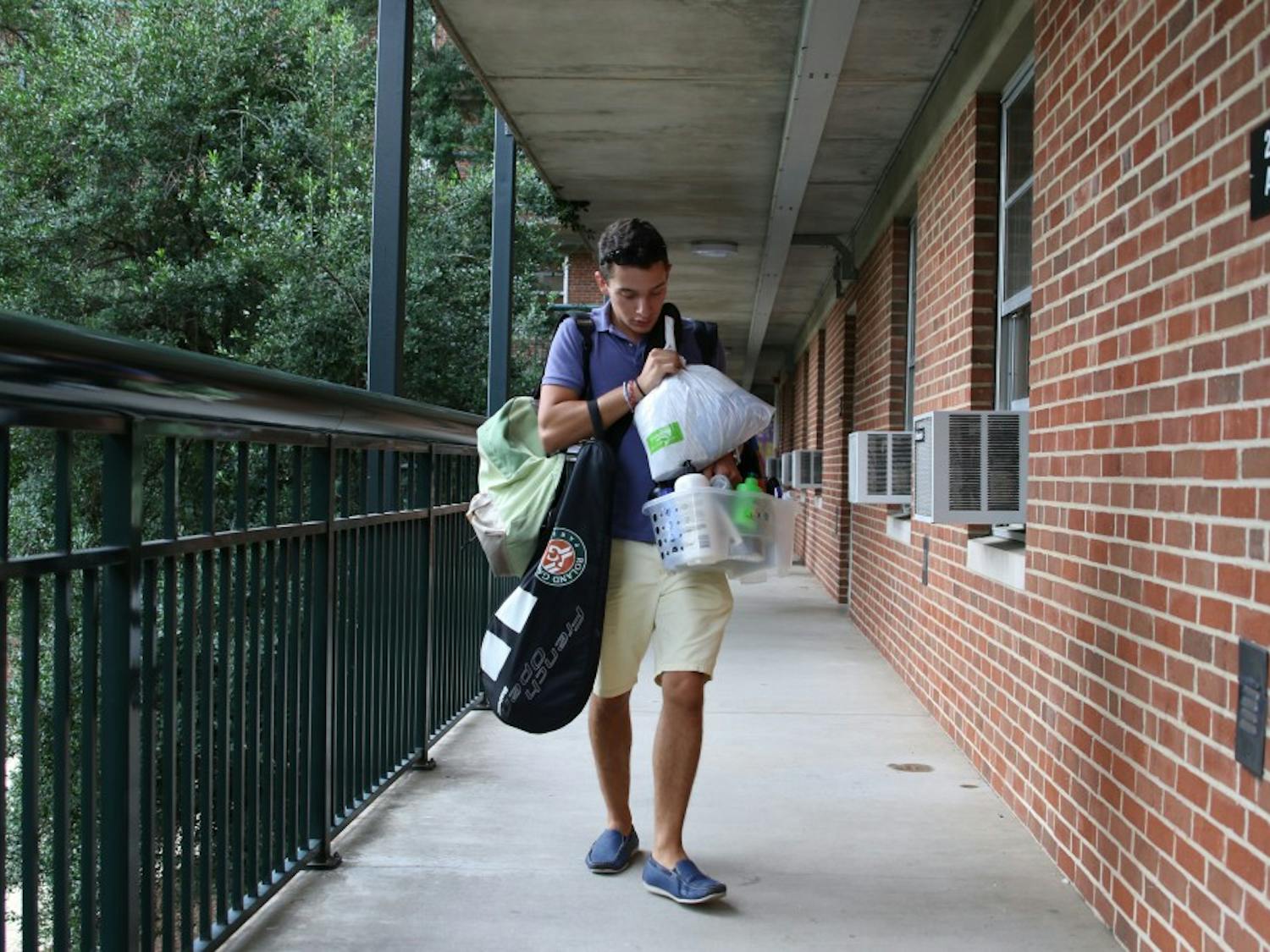 First year Albert Bell from Miami carries personal items towards his room in Hinton James on move in day.