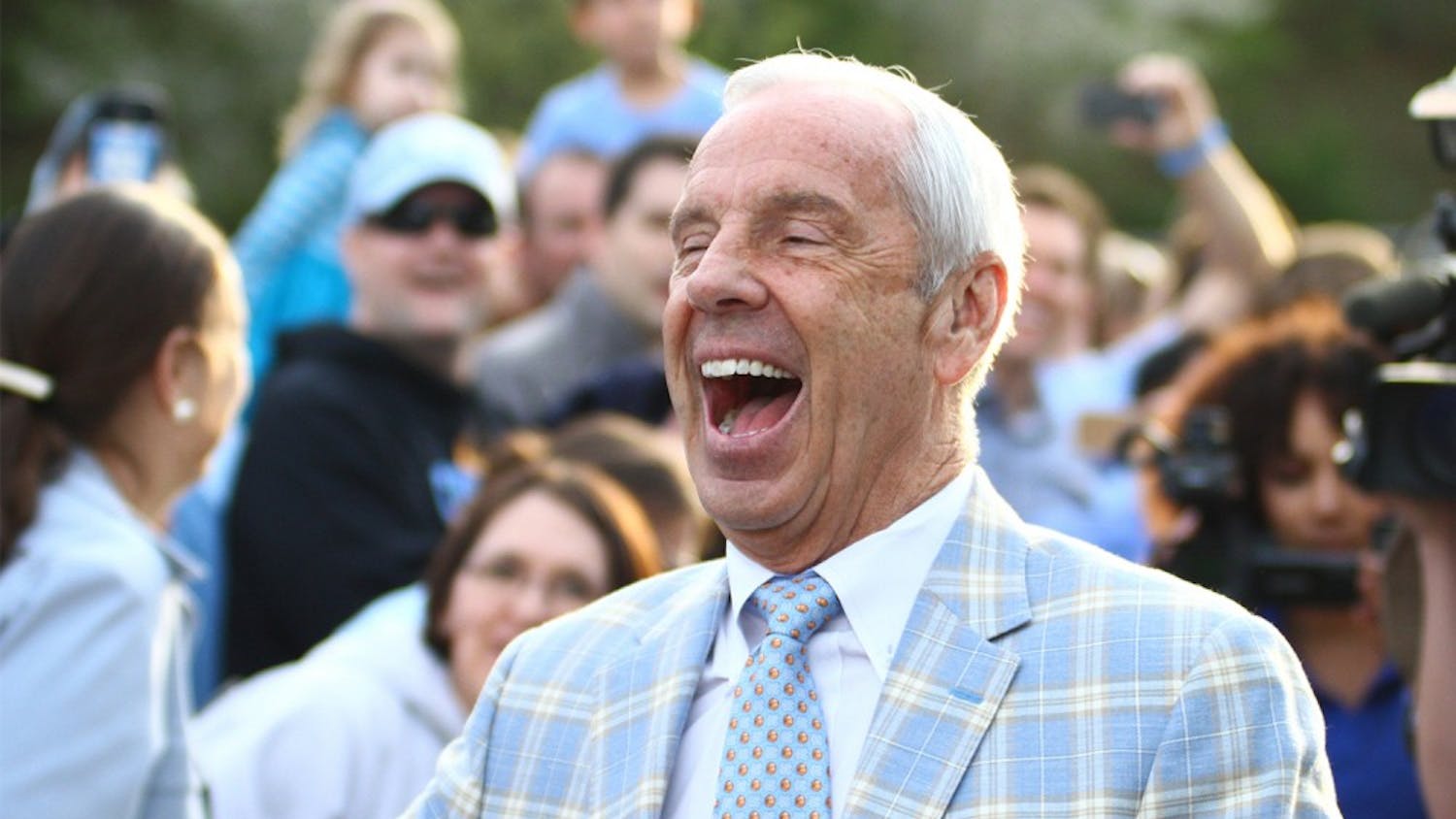 UNC men’s basketball coach Roy Williams laughs and waves to fans before getting on a bus to go to Houston for the Final Four.