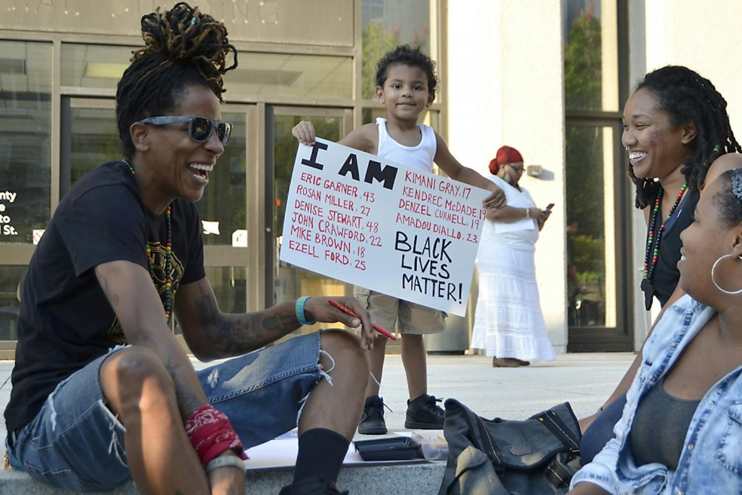 Nicky Souter (left), Braylen McCants (3) and Chay Shegog prepare posters for the National Moment of Silence for Victims of Police Brutality in Durham on Thursday evening. "It always hit so close to home," Shegog explains. "My family is from St. Louis and it could have been my cousin, my grandfather, anyone!"