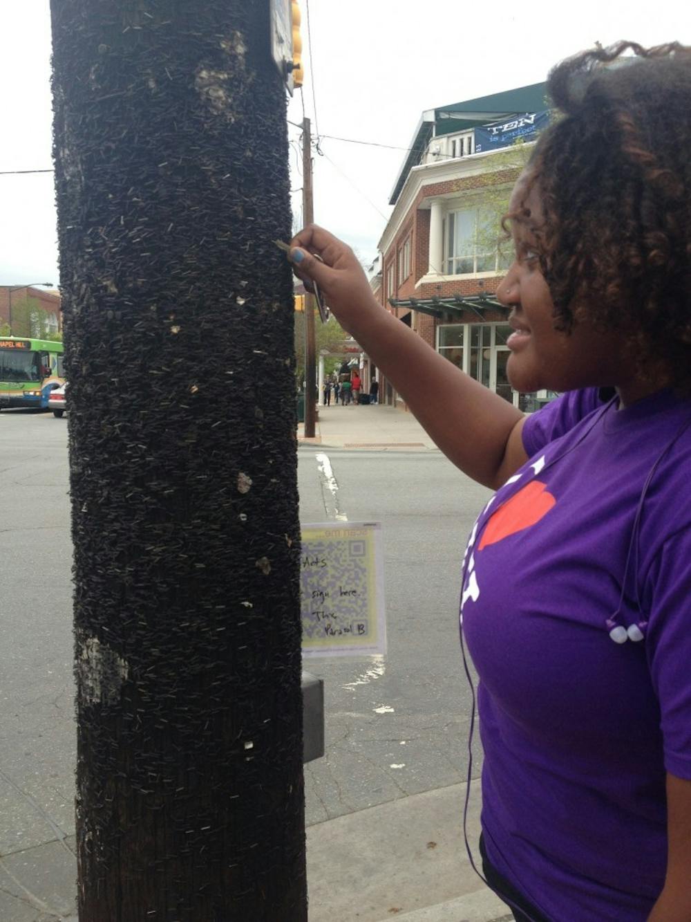 	<p>Junior Mariah Monsanto attempts to remove a staple with her keys from the light post on the corner of S. Columbia and Franklin St.</p>