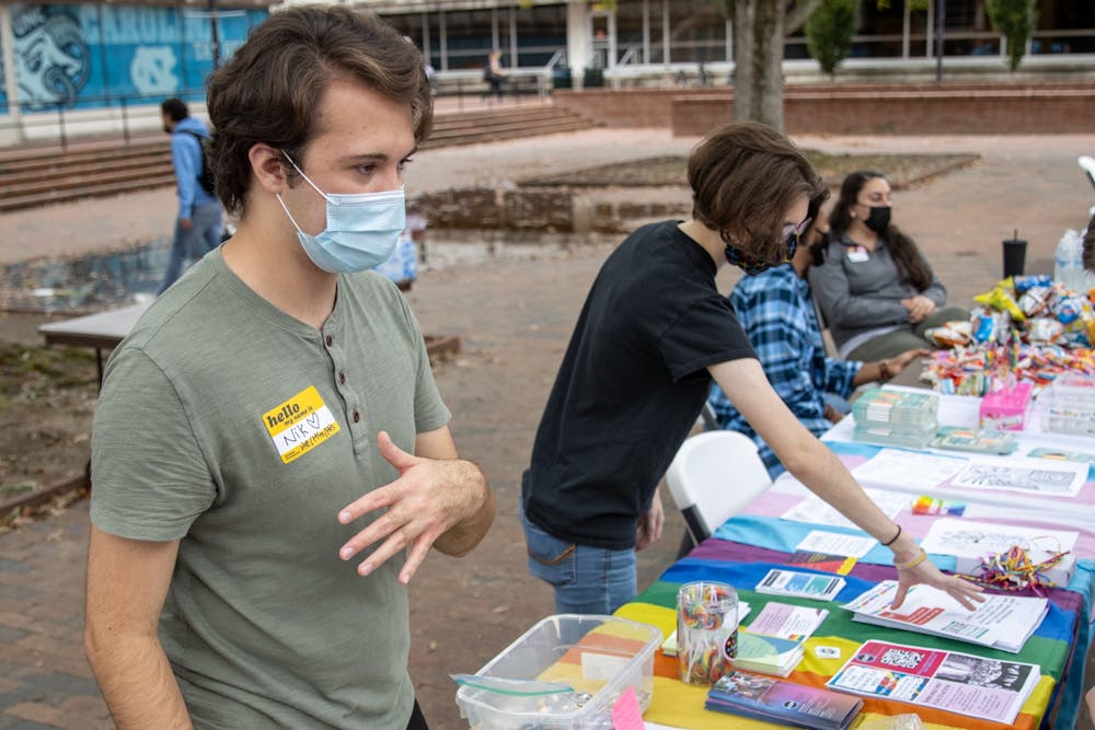 <p>Junior environmental studies major Nikalus Ward and senior biology major Rowan Merritt talk to patrons that visited the coming-out-day table in the Pit on Oct. 11. The event was sponsored by UNC's LGBTQ Center.&nbsp;</p>