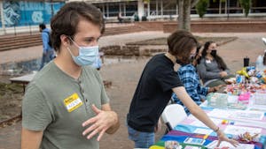 Junior environmental studies major Nikalus Ward and senior biology major Rowan Merritt talk to patrons that visited the coming-out-day table in the Pit on Oct. 11. The event was sponsored by UNC's LGBTQ Center.&nbsp;