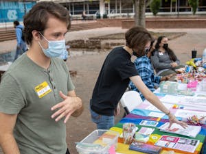 Junior environmental studies major Nikalus Ward and senior biology major Rowan Merritt talk to patrons that visited the coming-out-day table in the Pit on Oct. 11. The event was sponsored by UNC's LGBTQ Center.&nbsp;